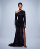 A woman wearing a floor-length, black one-shoulder gown made of silk burnout charmeuse with a leopard print pattern. The dress features one long sleeve, a fitted bodice, and a sheer lower panel with a high leg slit.