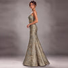 A woman models a strapless mermaid evening gown with a textured, metallic gold and silver floral jacquard pattern, set against a neutral gray studio background.