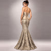 A woman modeling a strapless mermaid gown from the back, featuring a structured corset-style bodice with lace-up detailing and a shimmering champagne-gold patterned skirt, set against a neutral gray studio background.